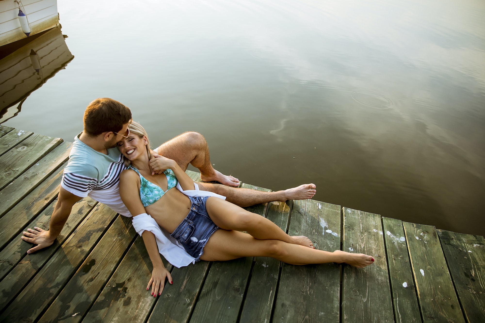 Loving couple sitting on the pier on lake